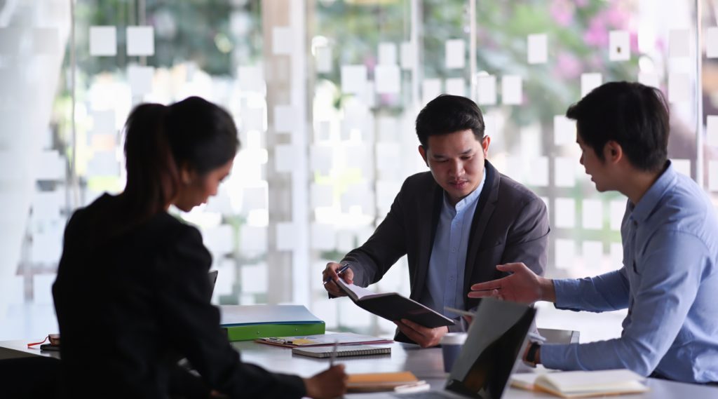 Image of business team analyzing documents and discussing business strategy at conference room.